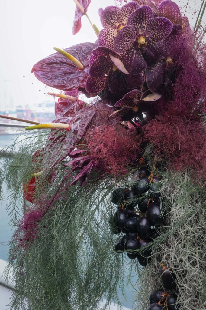 Dark anthurium tucked with black grapes at a VUE wedding, fruit in the florals