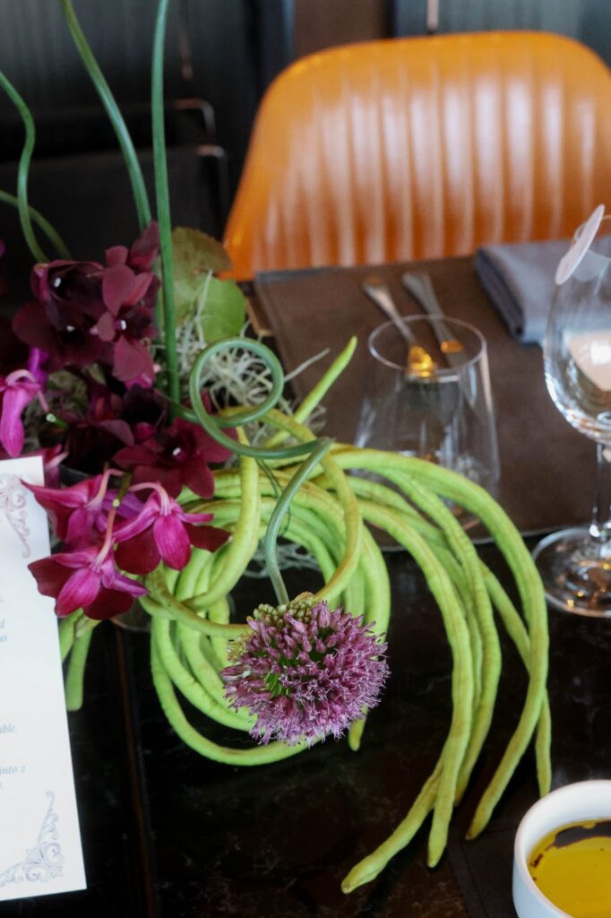 Orchid centrepiece with green tendrils at a dark and moody VUE wedding