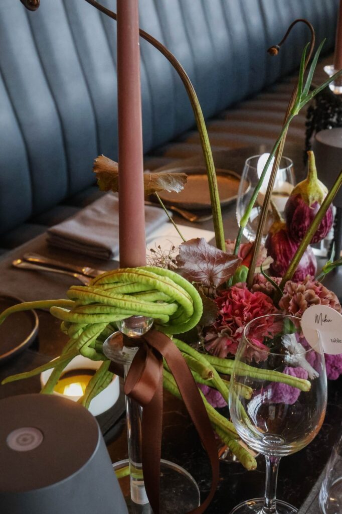 Petite bud vase against a blue banquette at a dark and moody VUE wedding