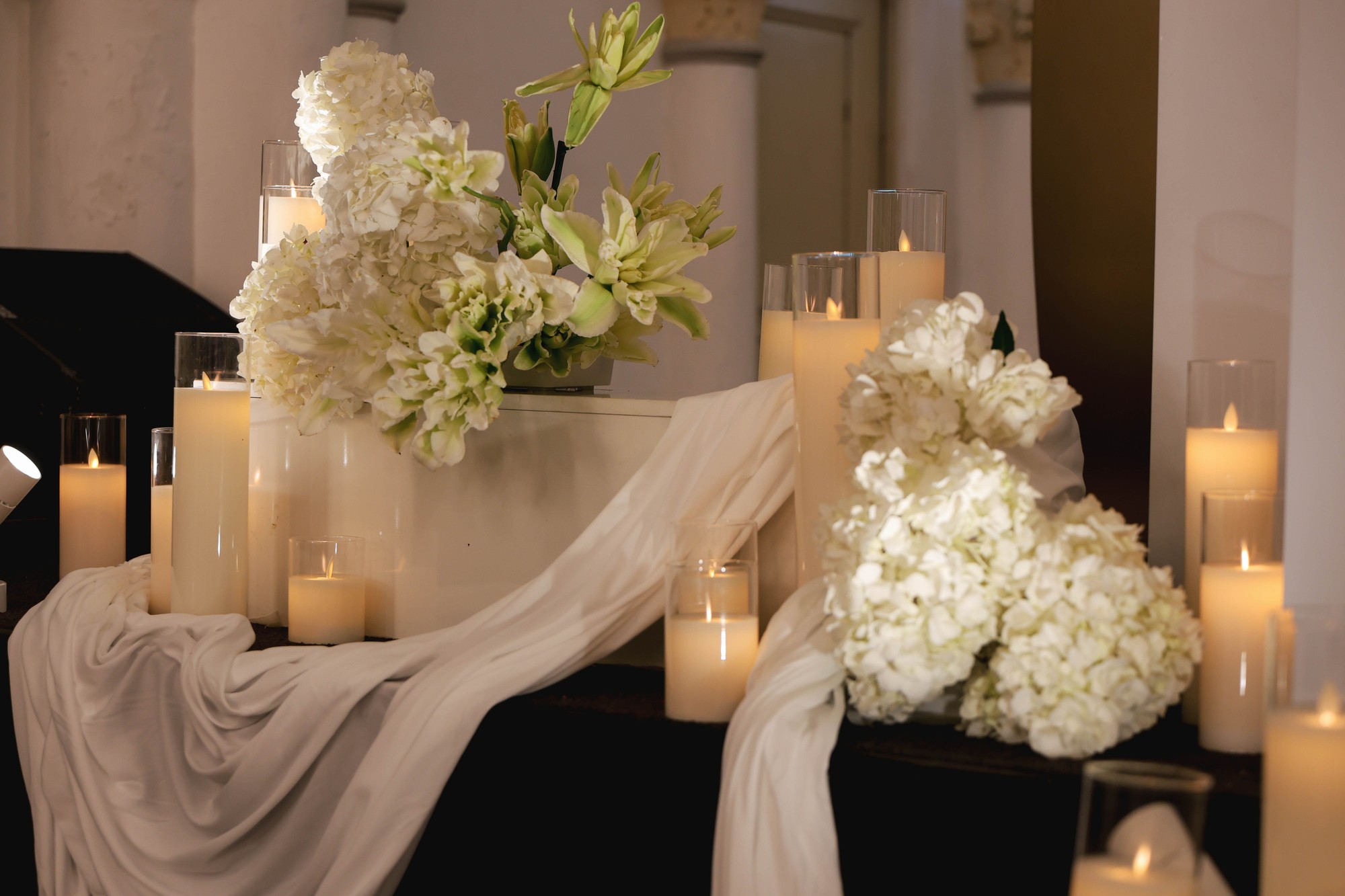 Chijmes candlelight wedding installation with white florals, draping and pillar candles