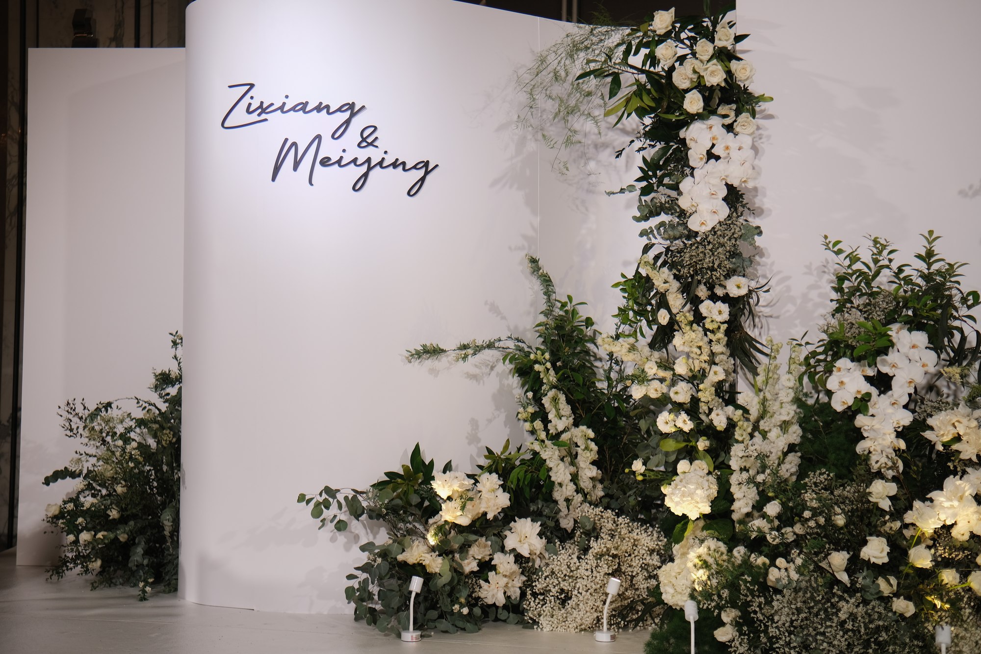 Shangri-La minimalist wedding with a curved white backdrop, the couple's names and soft white florals