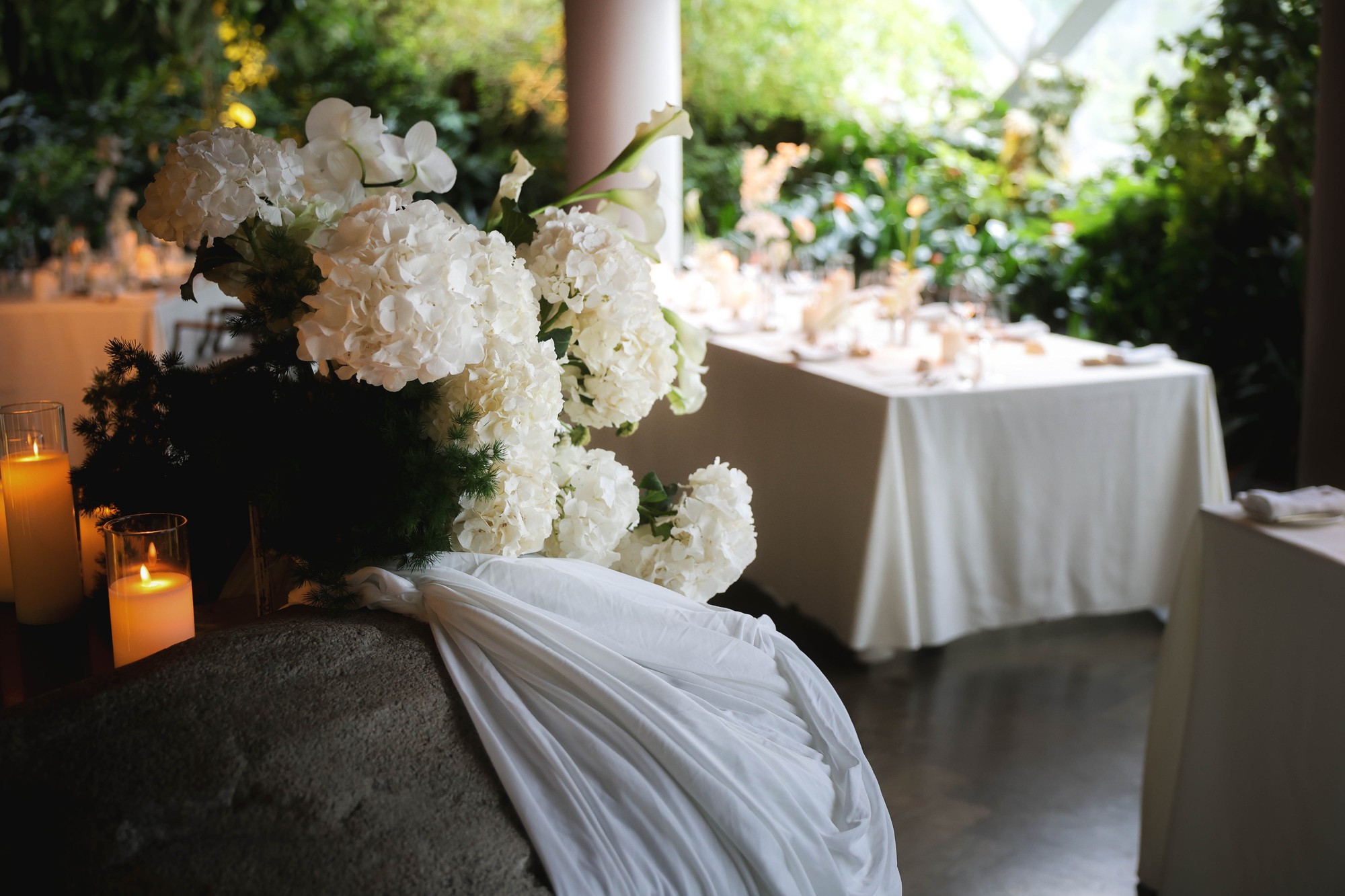 Garden-view dinner table at Hortus with white florals and candles, clean white and green wedding reception